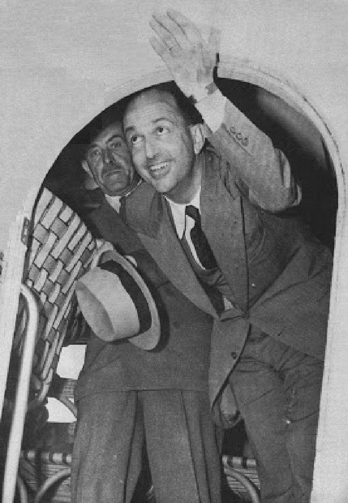 Umberto II di Savoia attraversa il portello di un aeroplano, reggendo il cappello nella mano destra. Nonostante l'occasione sorride. Era il 13 giugno 1946