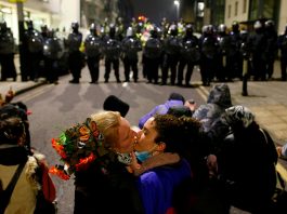 Ancora proteste a Bristol: 14 arresti, i manifestanti non si fermano Due manifestanti scambiano un bacio davanti alla fila di polizia antisommossa, durante le proteste a Bristol