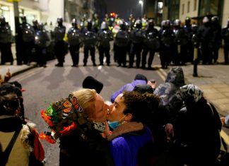 Ancora proteste a Bristol: 14 arresti, i manifestanti non si fermano Due manifestanti scambiano un bacio davanti alla fila di polizia antisommossa, durante le proteste a Bristol